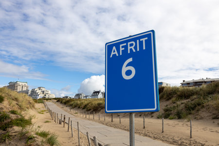 Beach sign with "exit 6" in dutch at Noordwijk aan Zee, the Netherlands with no people on the concrete path between dunesの写真素材