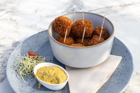 Dutch bitterbal in a bowl; traditional pub snack appetizer with mustard