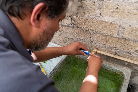 an old man fixing a broken tube of his own house