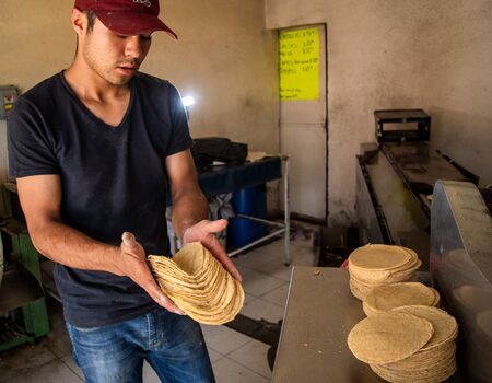 young man selling tortillas of nixtamal in typical mexican shopの写真素材