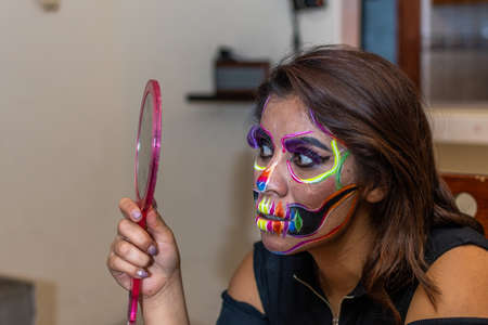 woman putting makeup on another woman for a party of the day of the dead