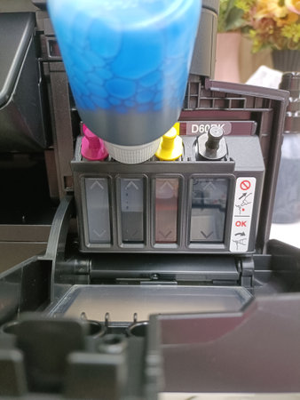Close-up. Refilling blue ink into a multifunction printer