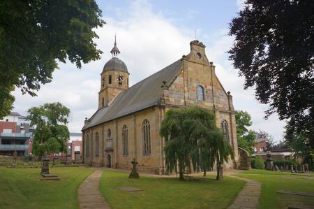 Church in a quiet field with a tree and a benchの写真素材
