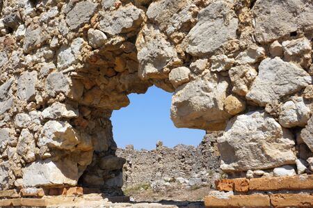View of a rocky arch and the ruins of Roman wallsの写真素材