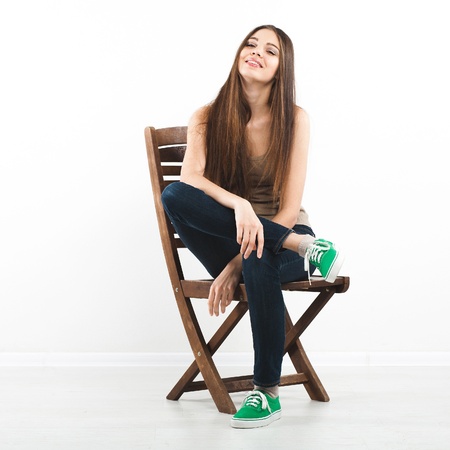 Beautiful young woman sitting on a chair over white backgroundの写真素材