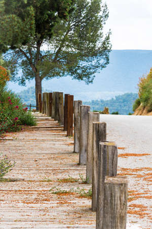 Wooden path with vegetation to the side, on the hill of Tossa de Montbui, La Anoia, Barcelona