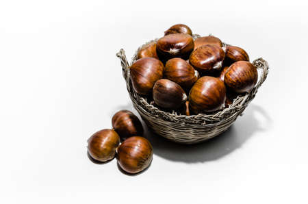 Chestnuts in wicker basket on white background