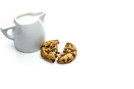 Close-up of homemade chocolate chip cookies with a jug of milk isolated on white background.の写真素材
