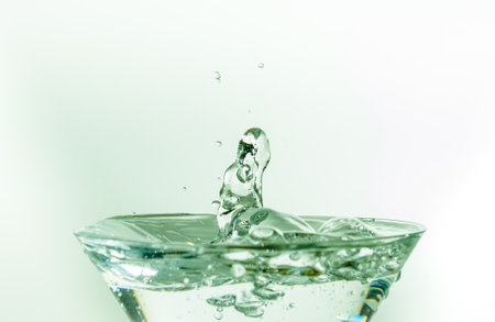 Close-up of water drop falling into a glassの写真素材