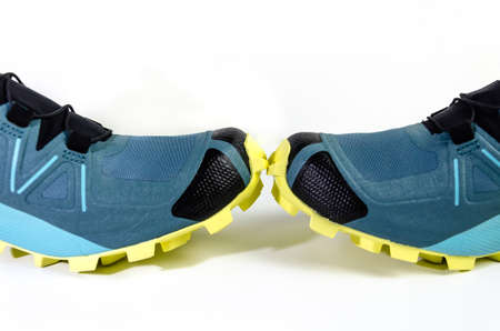 Pair of new blue sneakers with yellow sole, on white background. Shoes for mountain, trekkingの写真素材