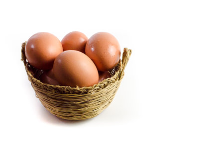 Fresh eggs inside a wicker basket on white background. Copy spaceの写真素材