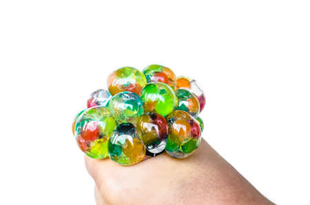 Hand of a girl squeezing a colorful stress ball on white background. Improved motor skillsの写真素材