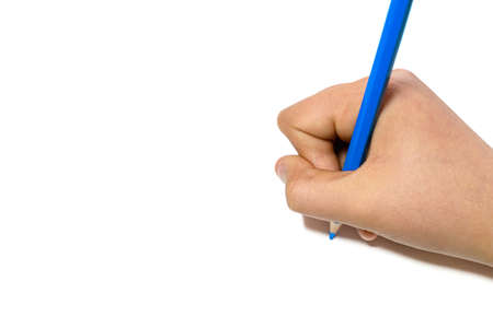 Girl's hand writing with a blue pencil on a white sheetの写真素材