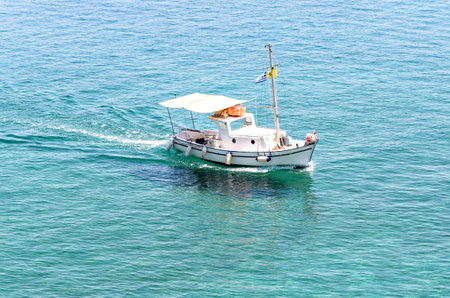 Small fishing boat on the crystal clear beach of Corfu, Greeceの写真素材