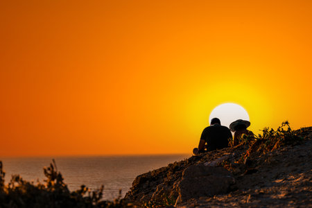 Young couple watching the sunset on the Barbate beach next to the Trafalgar lighthouse, CÃ¡dizの写真素材