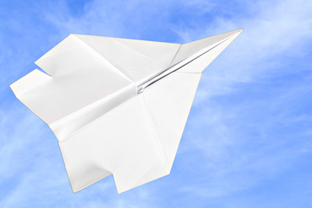 White paper plane isolated over blue sky with white cloudsの写真素材