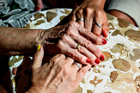 Affection and tenderness of a granddaughter to her grandmother. Traits of aging on the handsの写真素材