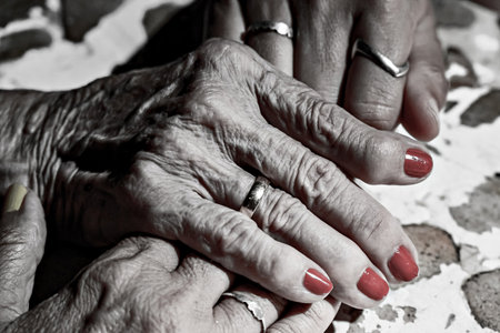 Affection and tenderness of a granddaughter towards her grandmother. Signs of aging in the hands. Black and white effectの写真素材
