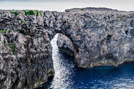 Spectacular sunset at Pont d'en Gil â Cala Corbetar in Ciutadella, Menorca, Balearic Islands. Peculiar natural formation in the form of an archの写真素材