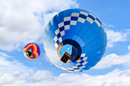 Colorful hot air balloon flying over blue sky with white cloudsの写真素材