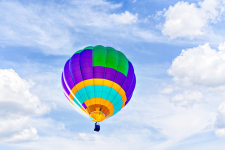 Colorful hot air balloon flying over blue sky with white cloudsの写真素材
