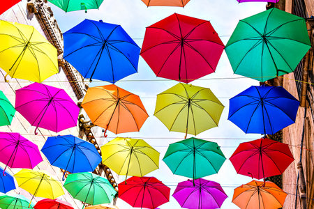Background of many hanging colorful umbrellas decorating the street of a townの写真素材