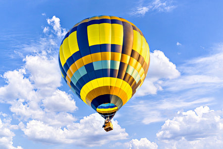 Colorful hot air balloon flying over blue sky with white cloudsの写真素材