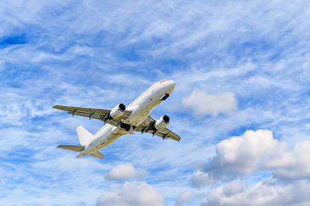 Passenger plane landing at the airport, under a blue sky with white cloudsの写真素材