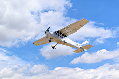 Single engine ultralight plane flying in the blue sky with white cloudsの写真素材