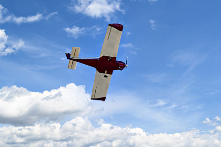 Single engine ultralight plane flying in the blue sky with white cloudsの写真素材