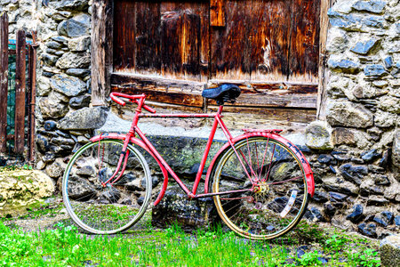 Red vintage bicycle next to a rustic stone house in the village of Viella, in the Aran Valley, Catalonia, Spainの写真素材