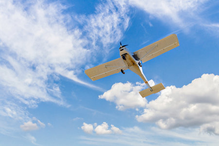 Single engine ultralight plane flying in the blue sky with white cloudsの写真素材