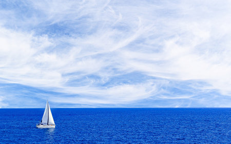Boat, sailboat sailing under a blue sky with white cloudsの写真素材