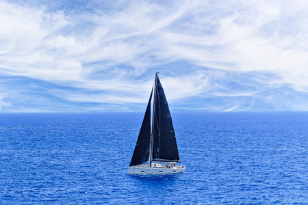 Boat, sailboat sailing under a blue sky with white cloudsの写真素材