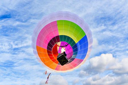 Colorful hot air balloon flying over blue sky with white cloudsの写真素材