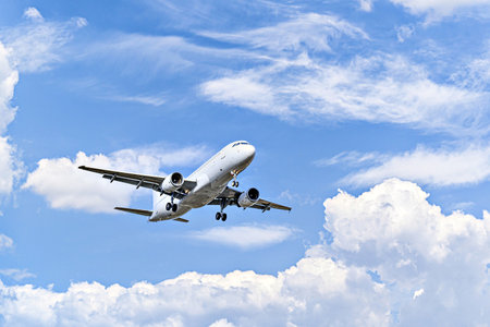 Passenger plane landing at the airport, under a blue sky with white cloudsの写真素材