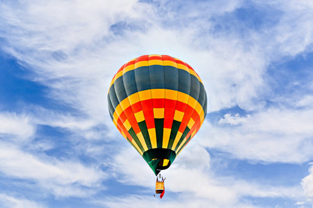 Colorful hot air balloon flying over blue sky with white cloudsの写真素材