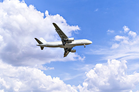 Passenger plane landing at the airport, under a blue sky with white cloudsの写真素材