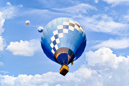 Colorful hot air balloon flying over blue sky with white cloudsの写真素材