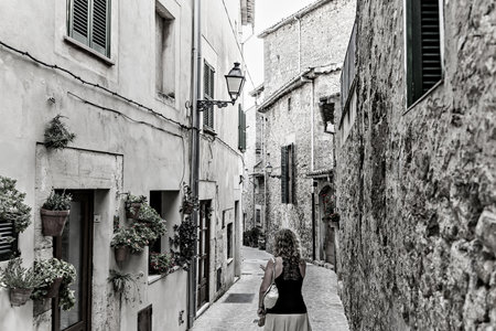 Blonde woman with curly hair walking along a street in the picturesque and famous town of...