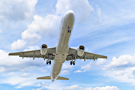 Passenger plane landing at the airport, under a blue sky with white cloudsの写真素材