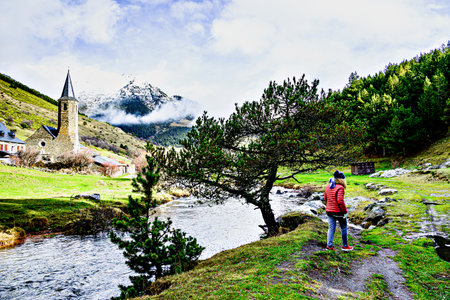 Woman in red coat visiting the Montgarri Sanctuary, located in the municipality of Alto ArÃ¡n in the Pyrenees of Lleida, Catalonia, Spainの写真素材