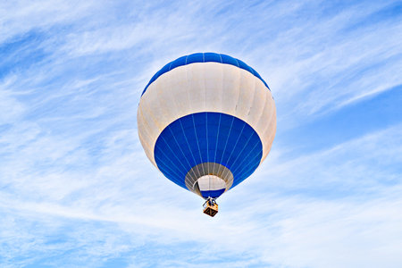 Colorful hot air balloon flying over blue sky with white cloudsの写真素材