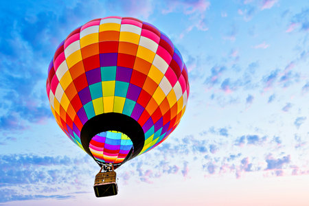 Colorful hot air balloon flying over blue sky with white cloudsの写真素材