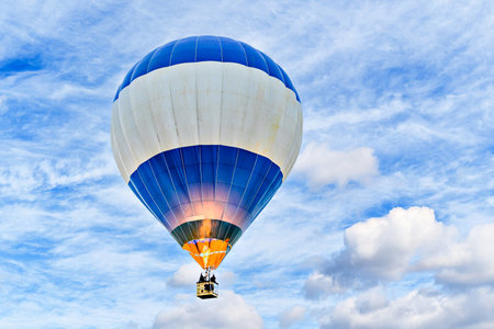 Colorful hot air balloon flying over blue sky with white cloudsの写真素材