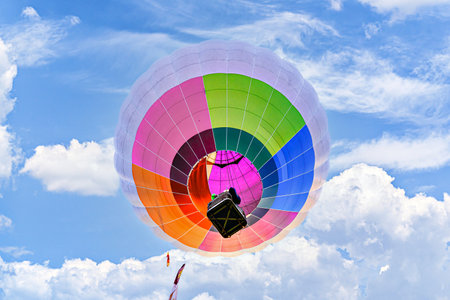Colorful hot air balloon flying over blue sky with white cloudsの写真素材