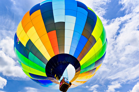 Colorful hot air balloon flying over blue sky with white cloudsの写真素材
