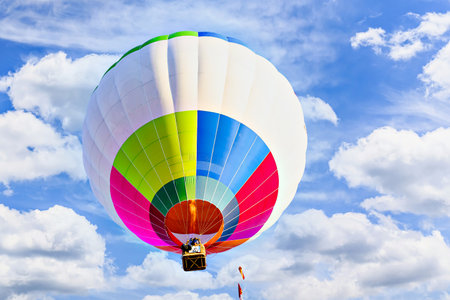 Colorful hot air balloon flying over blue sky with white cloudsの写真素材