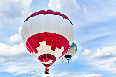 Colorful hot air balloon flying over blue sky with white cloudsの写真素材