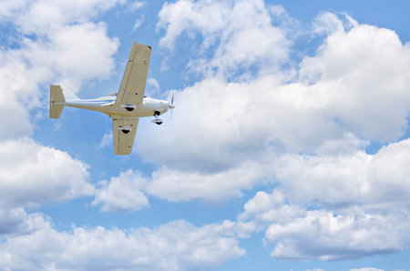 small airplane flying in the blue sky with white clouds on a sunny day